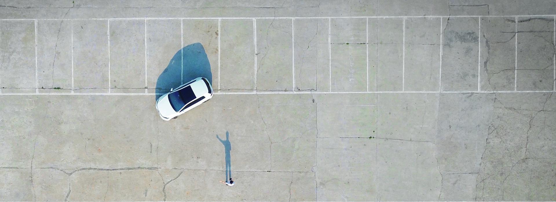 Auto en persoon op een parkeerplaats vanuit de lucht gezien