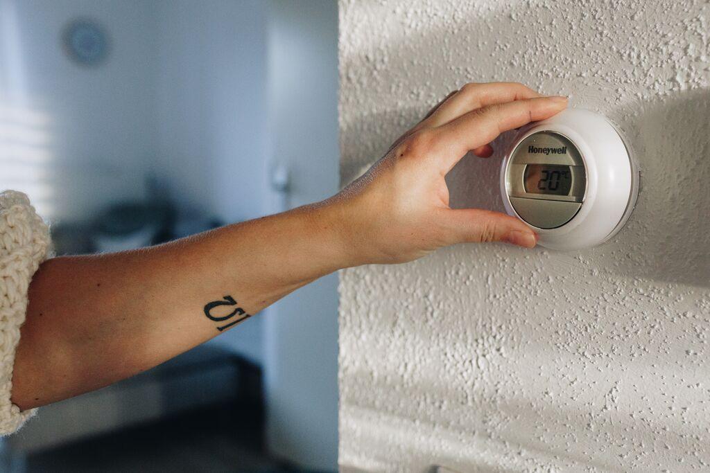 Iemand verandert de temperatuur via een thermostaat