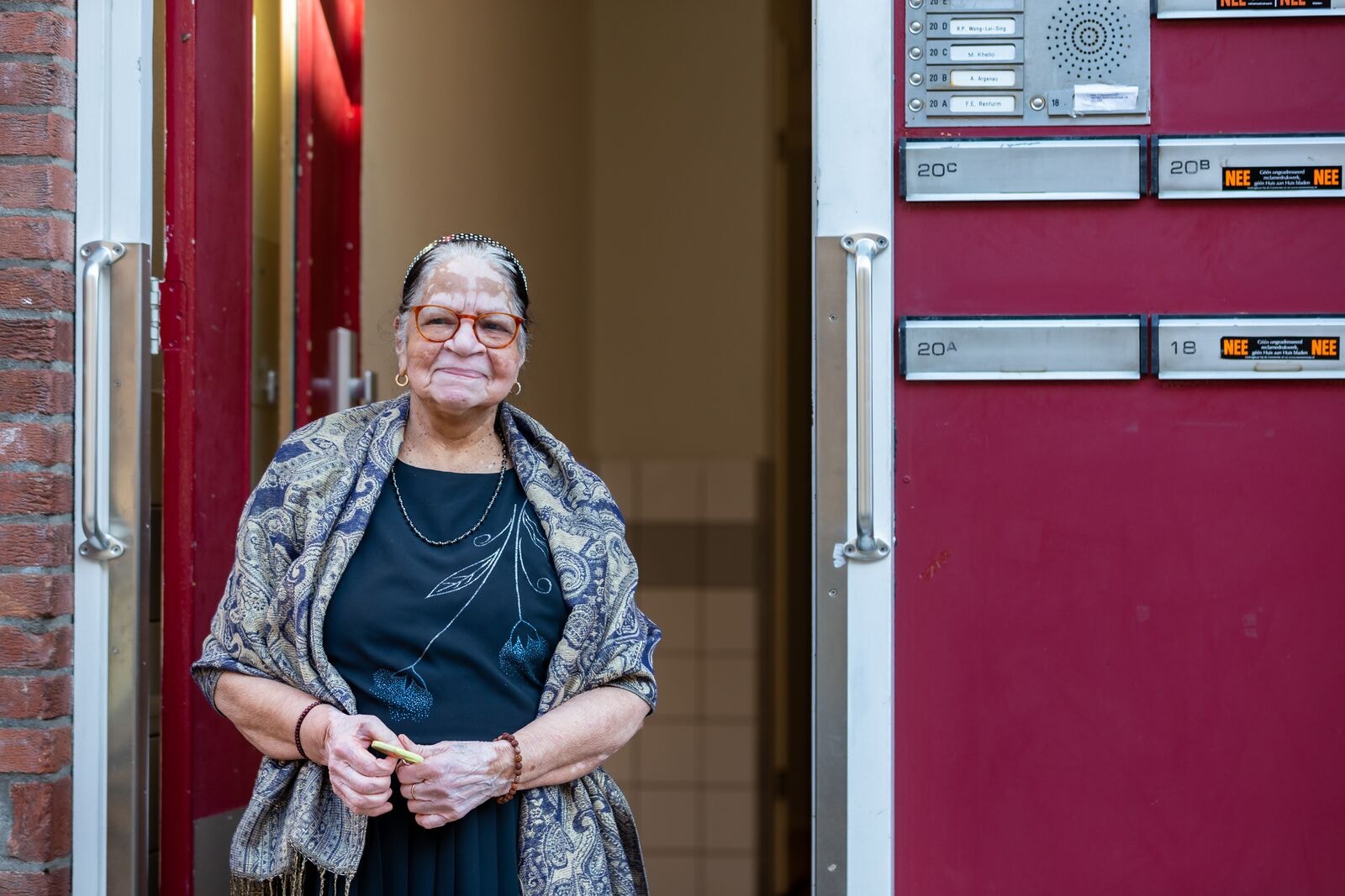 Mevrouw Ganesh in de deuropening van de portiek