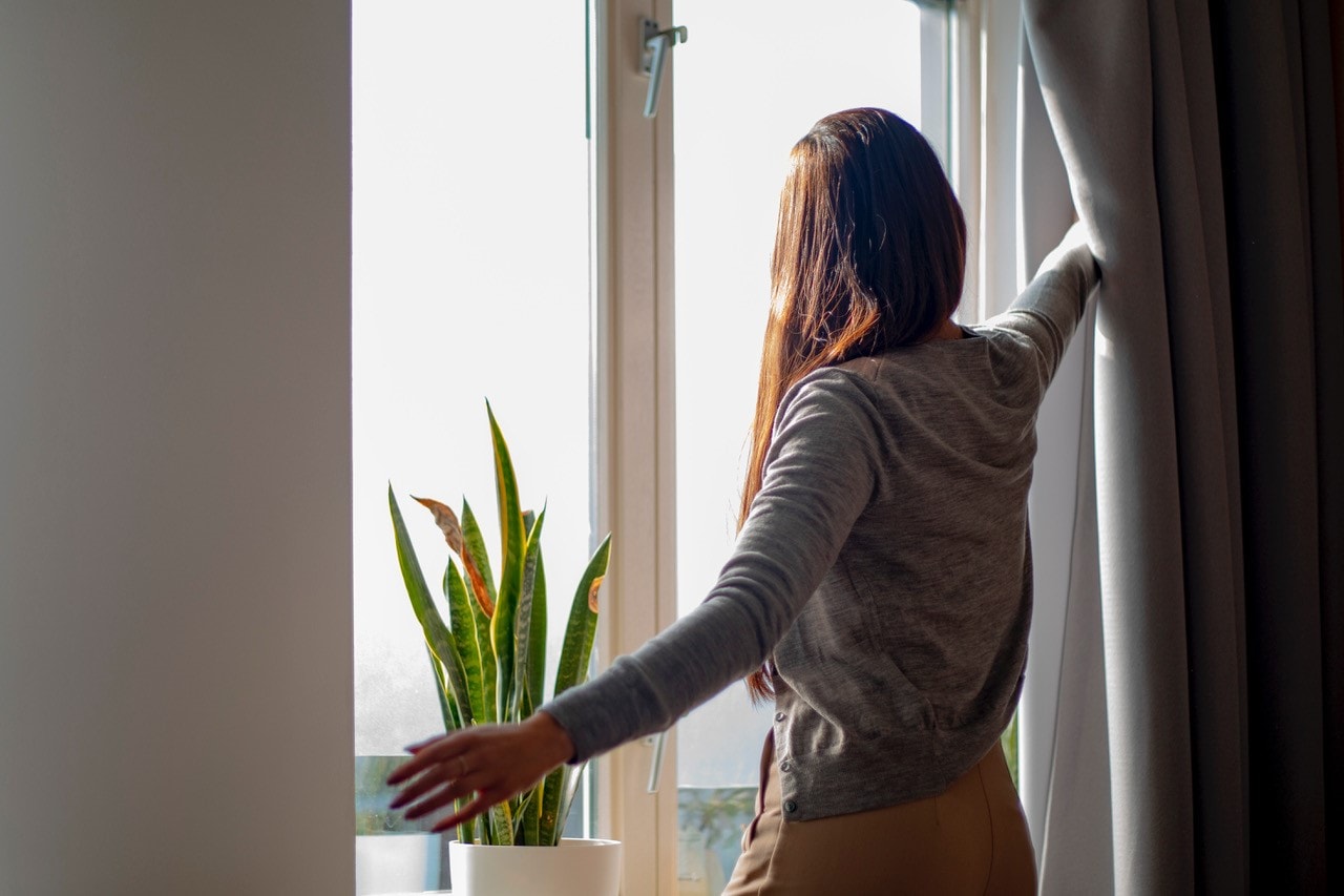 Vrouw doet gordijn open