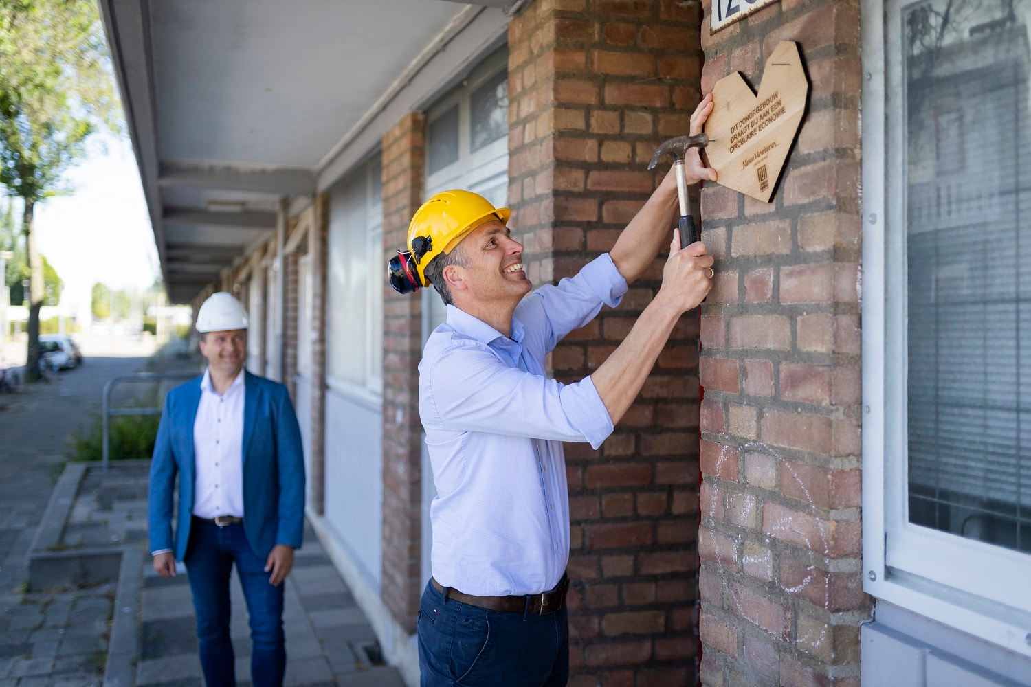 Alex en Alexander spijkeren houten hart vast aan de muur