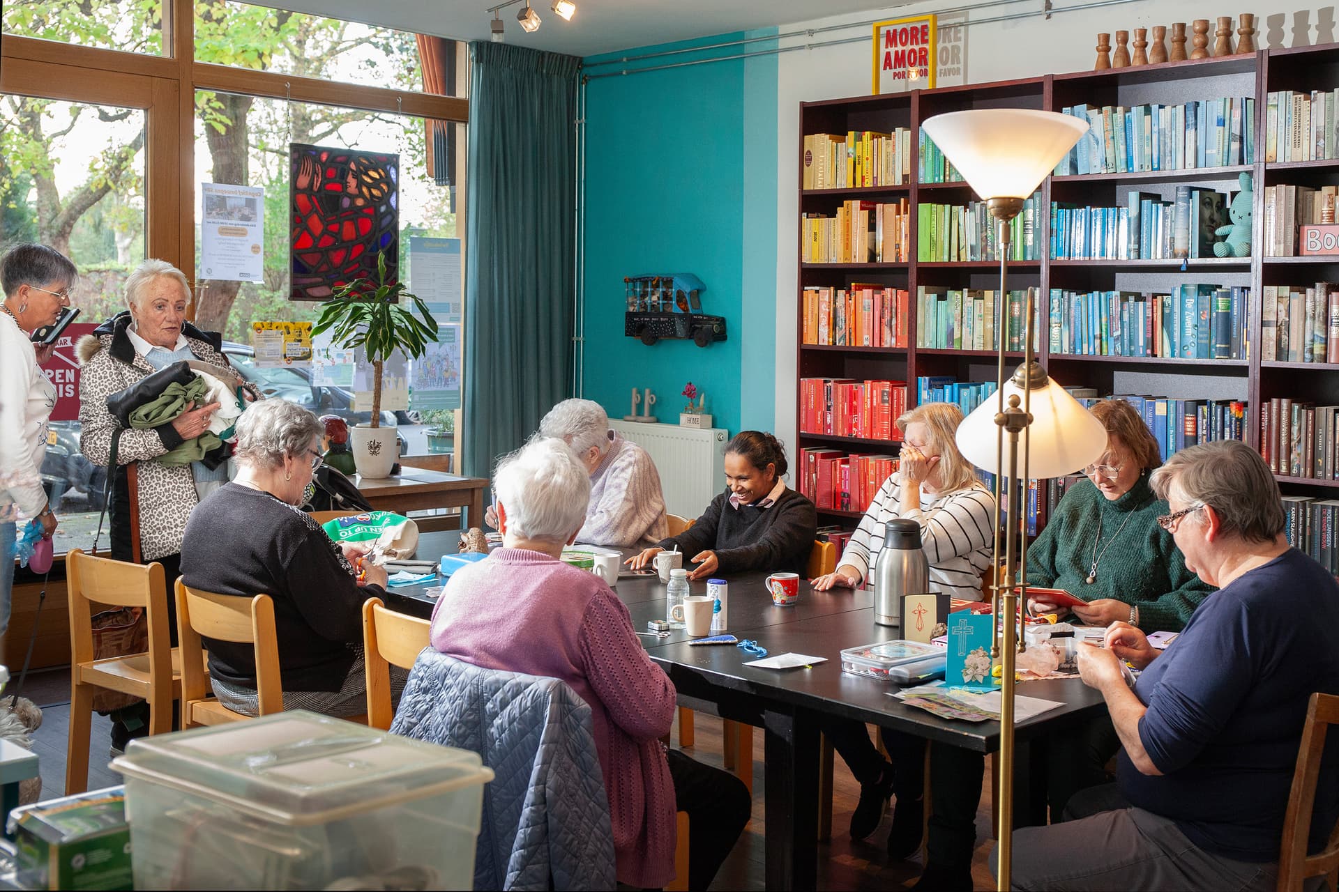 Een groep bezoekers zit binnen aan een tafel in Open Huis Crooswijk