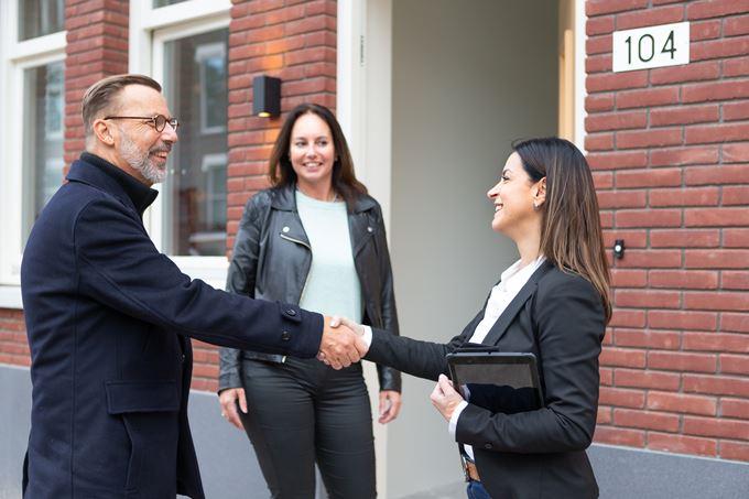 Man en vrouw ontmoeten makelaar voor woning