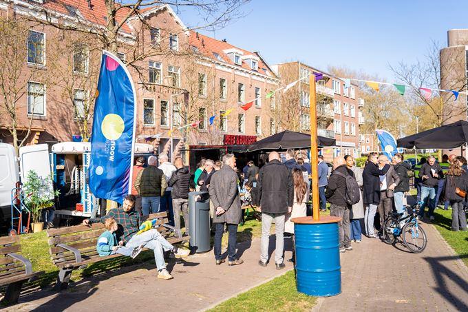 Feest aan de Bellamystraat waar mensen bij elkaar staan, tussen kraampjes met eten