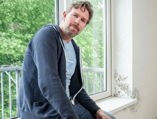 Medewerker van Woonstad zit op een kozijn met lichte schimmel