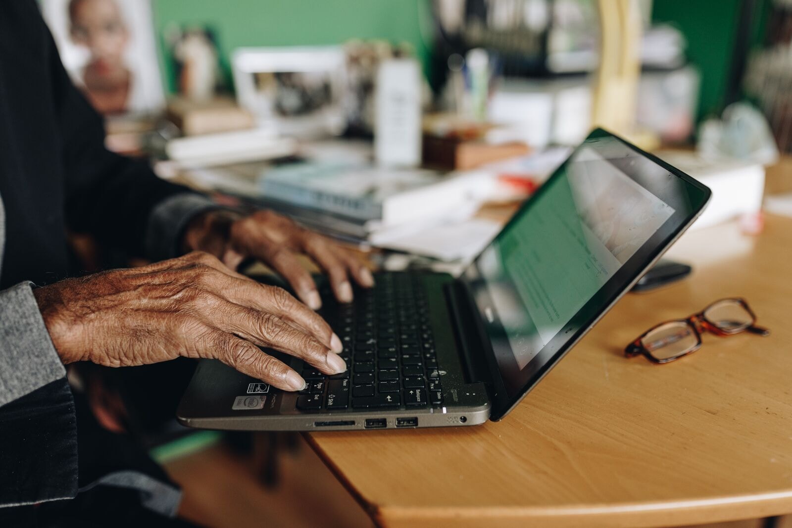 Handen boven een laptop die op tafel staat