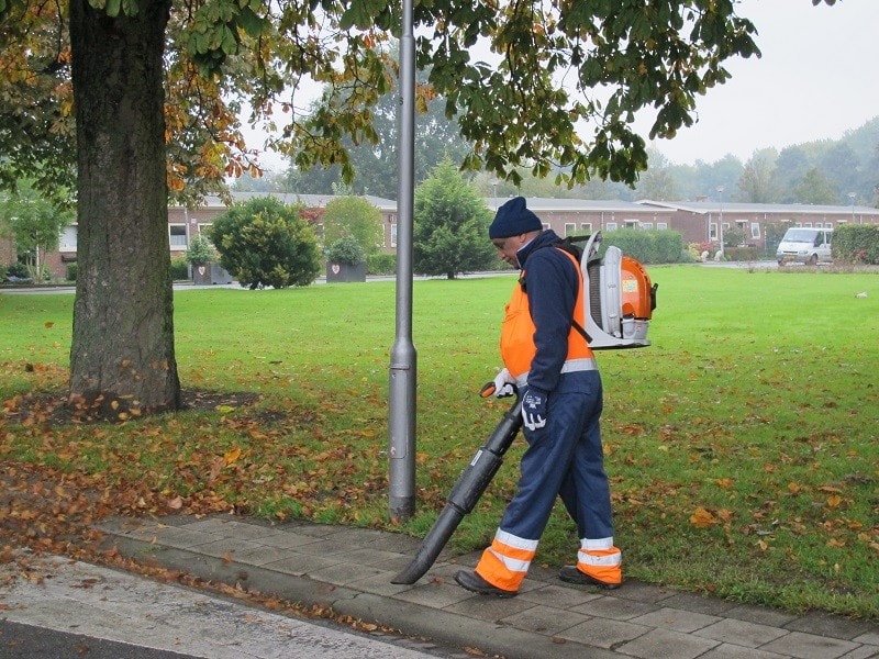 Man met oranje hesje en bladblazer