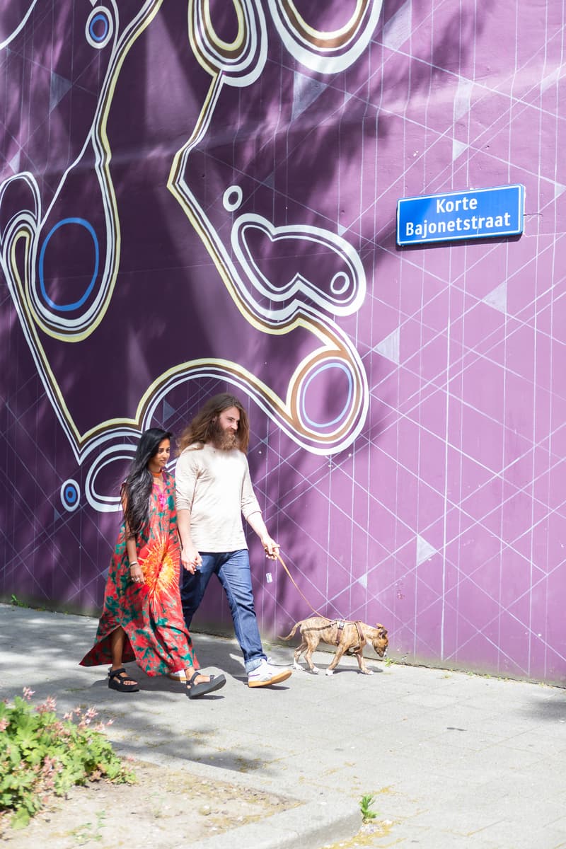 Parricia en Maxim laten de hond uit voor een muur met paarse street art