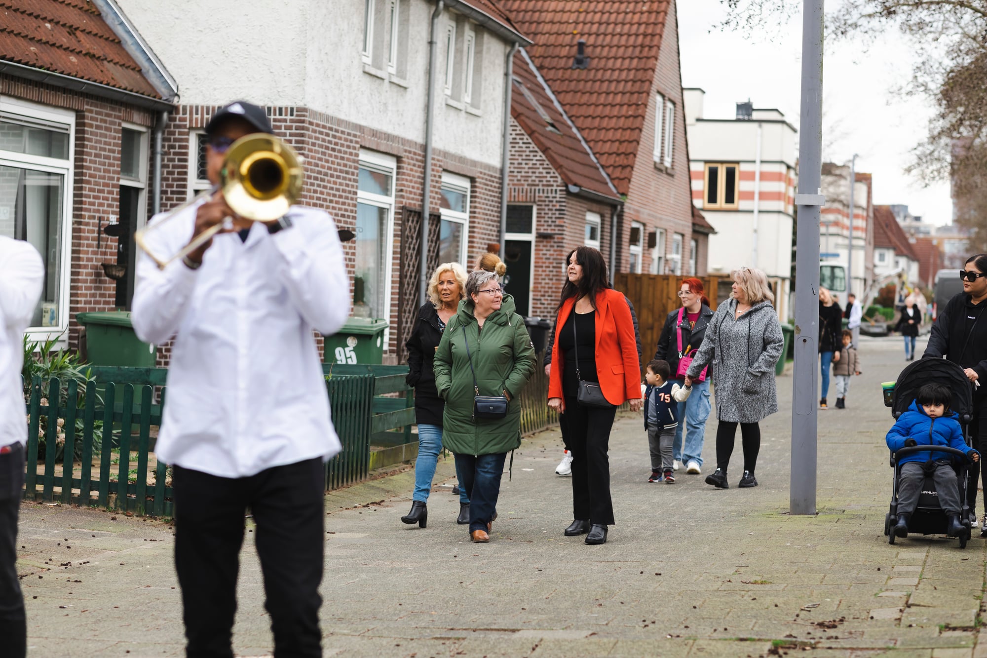 Bewoners en trompetspeler op straat, met bewoners op de achtergrond