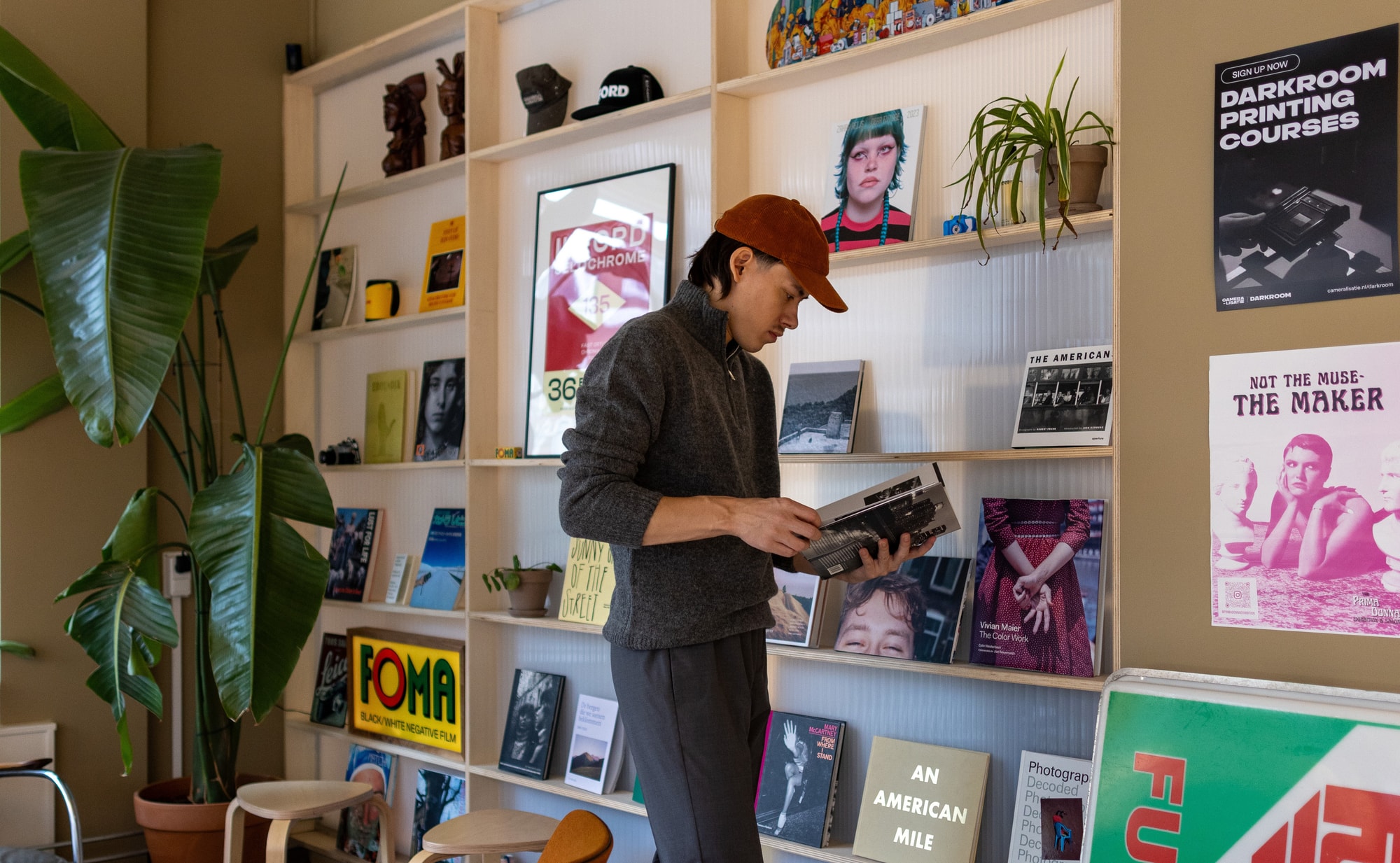 Woody bladert door een fotoboek en staat voor en wand met fotoboeken en prints