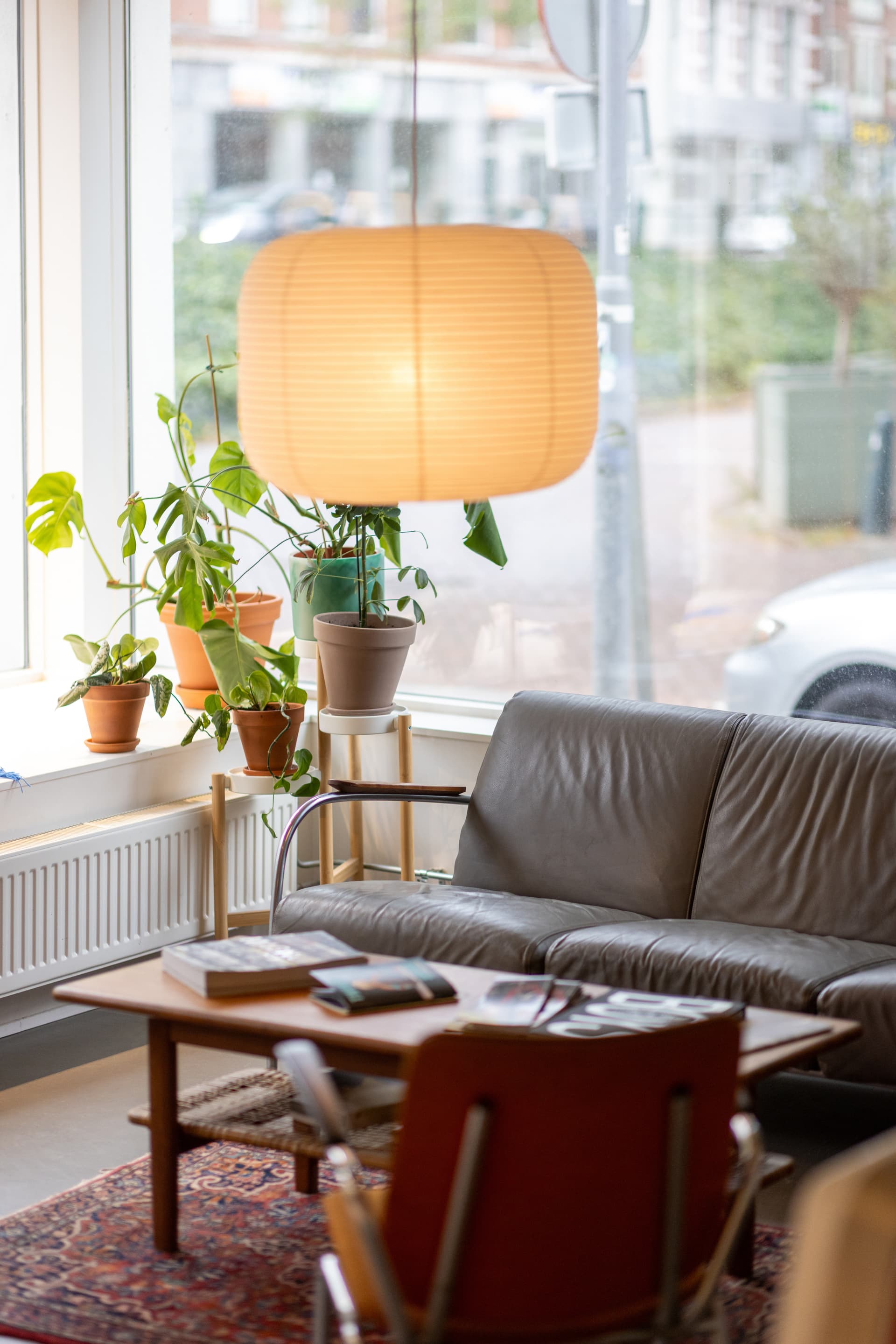 De woonkamerhoek van Cameralisatie, met een leren bank, houten koffietafel, planten en warme lamp