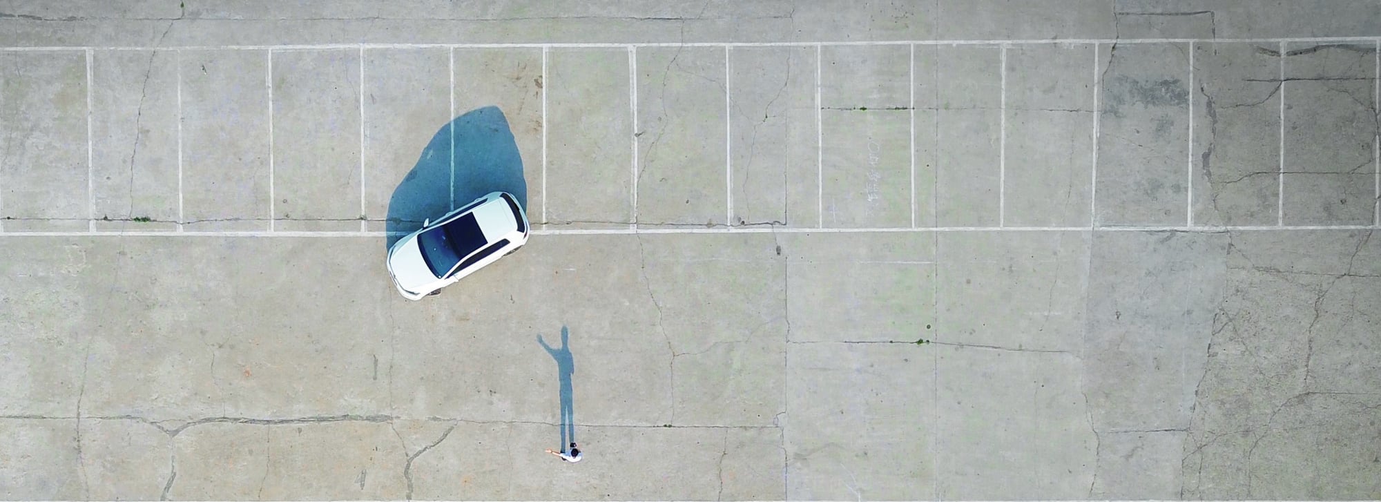 Auto en persoon op een parkeerplaats vanuit de lucht gezien