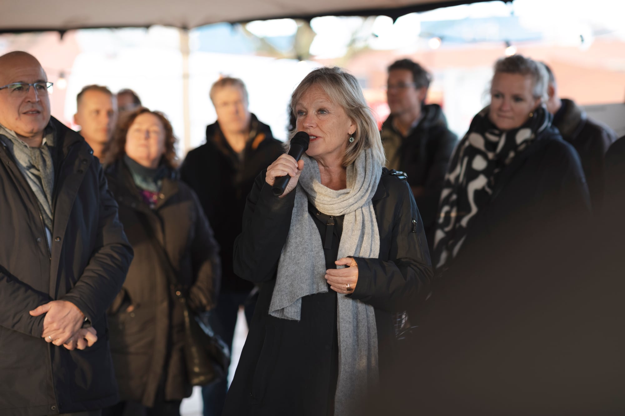 Een vrouw spreekt een groep mensen toe bij de start van de bouw van nieuwbouw project Kop Dakpark
