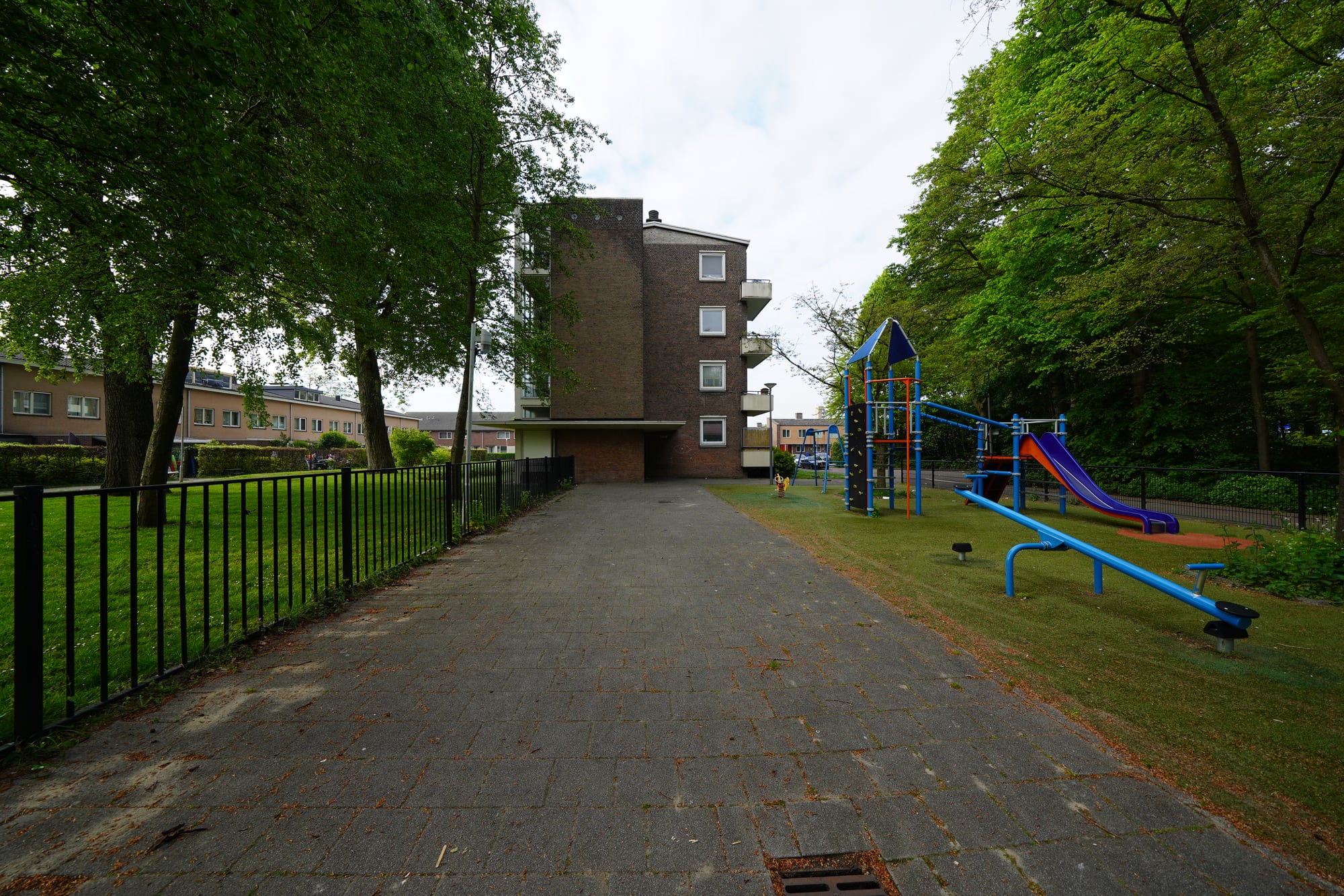 Flatgebouw aan de zijkant te zien vanuit de speeltuin
