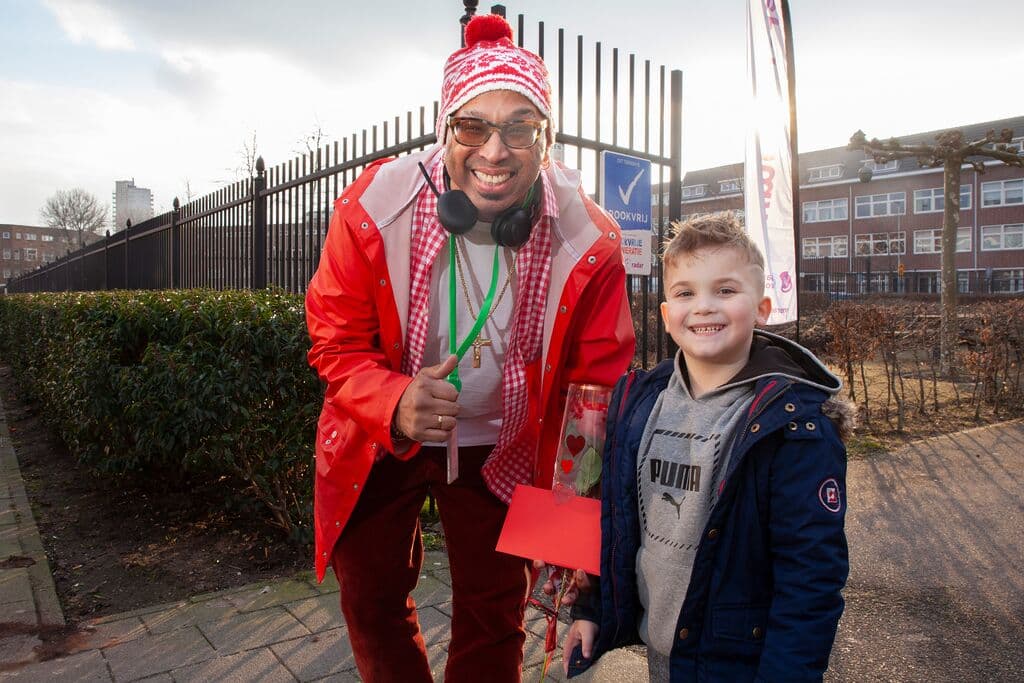 Een man met een muts op en een jongen kijken lachend in de camera