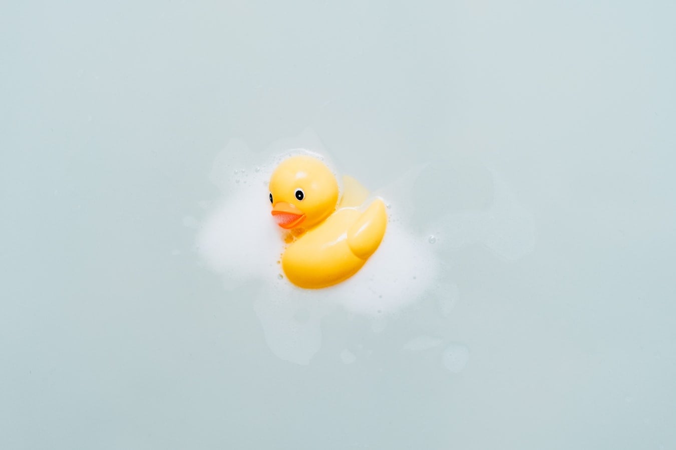 Gele badeend in het water met badschuim