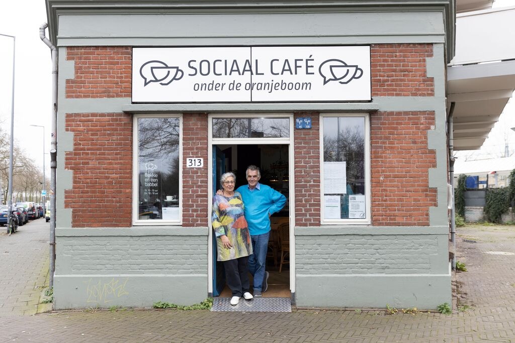 Entree Sociaal Café onder de Oranjeboom. Sjaak en Clare staat in de deuropening.