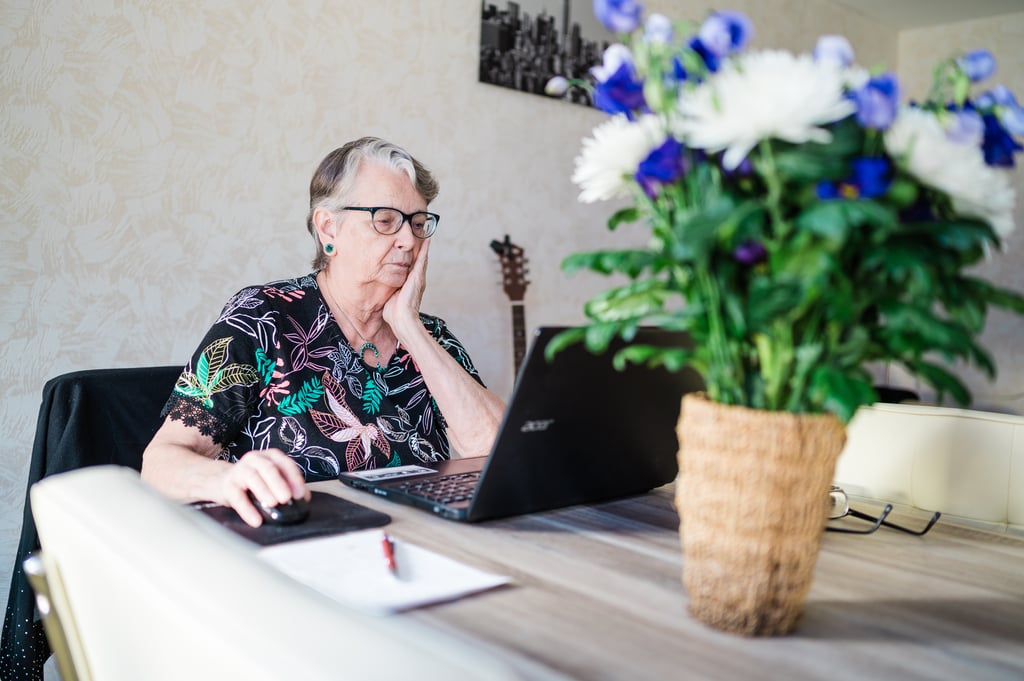 Mevrouw Weeda zittend aan tafel achter laptop