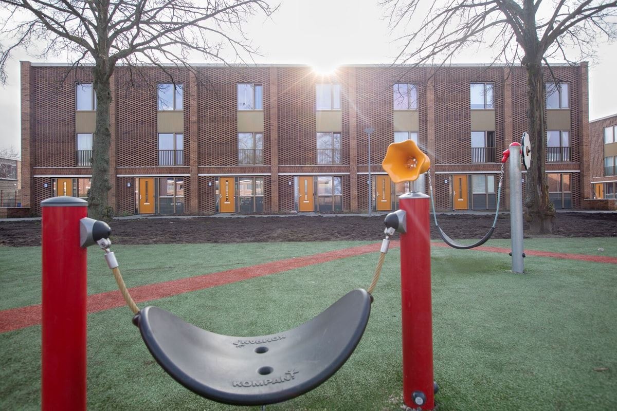 Woningen in Pendrecht met op de voorgrond een schommel op een speelplaats voor kinderen