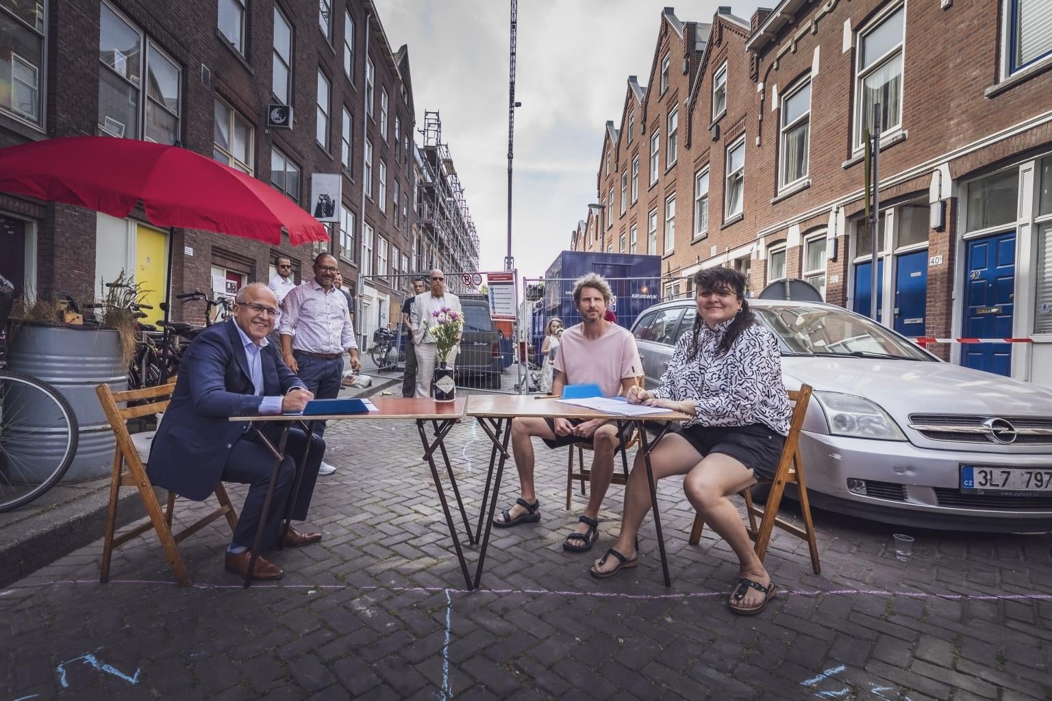 Groepsfoto met Mohamed aan tafel op straat