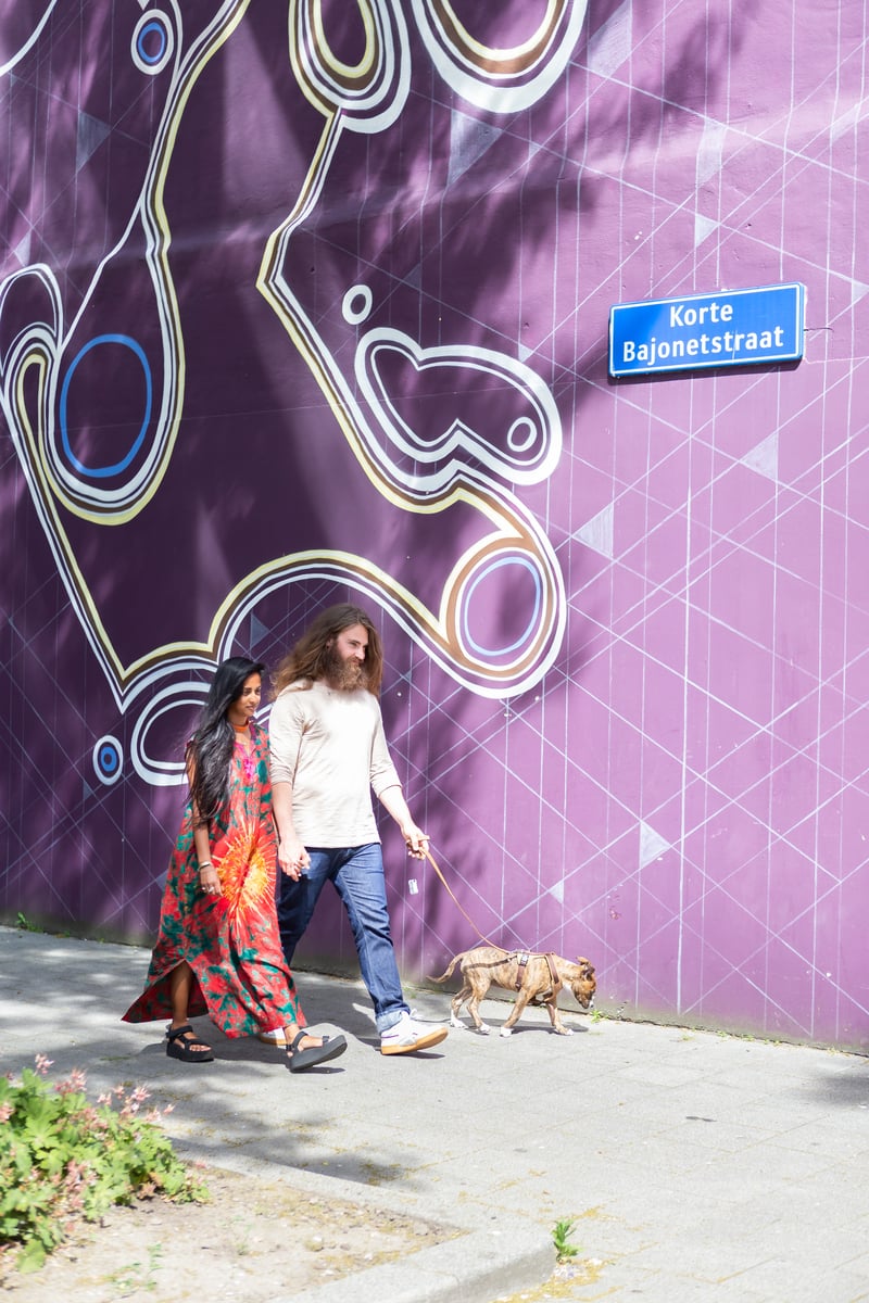 Parricia en Maxim laten de hond uit voor een muur met paarse street art