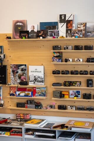Analoge camera's en fotoboeken uitgestald op houten planken tegen een muur