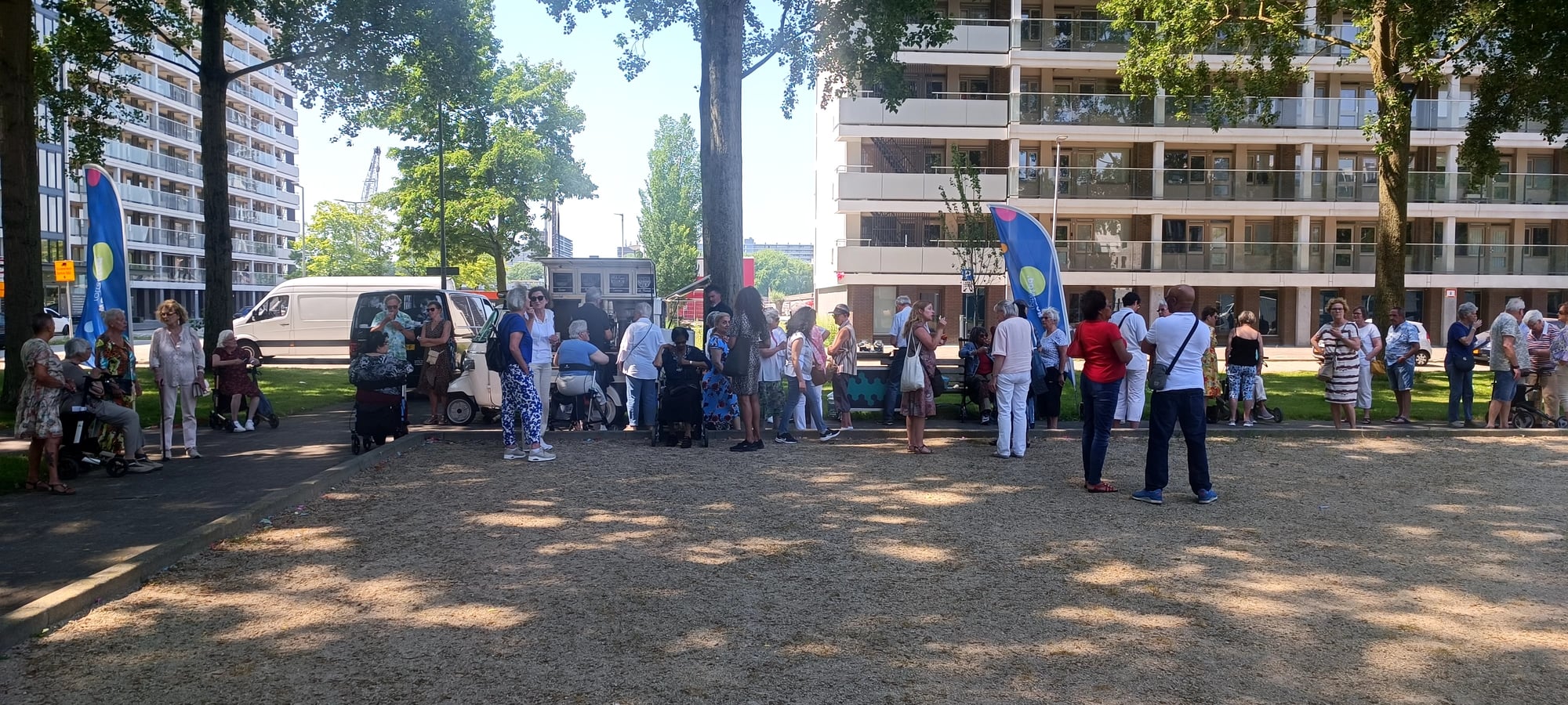 Een groep bewoners die genieten van het straatfeest van de heropening van de Prinsessenflats