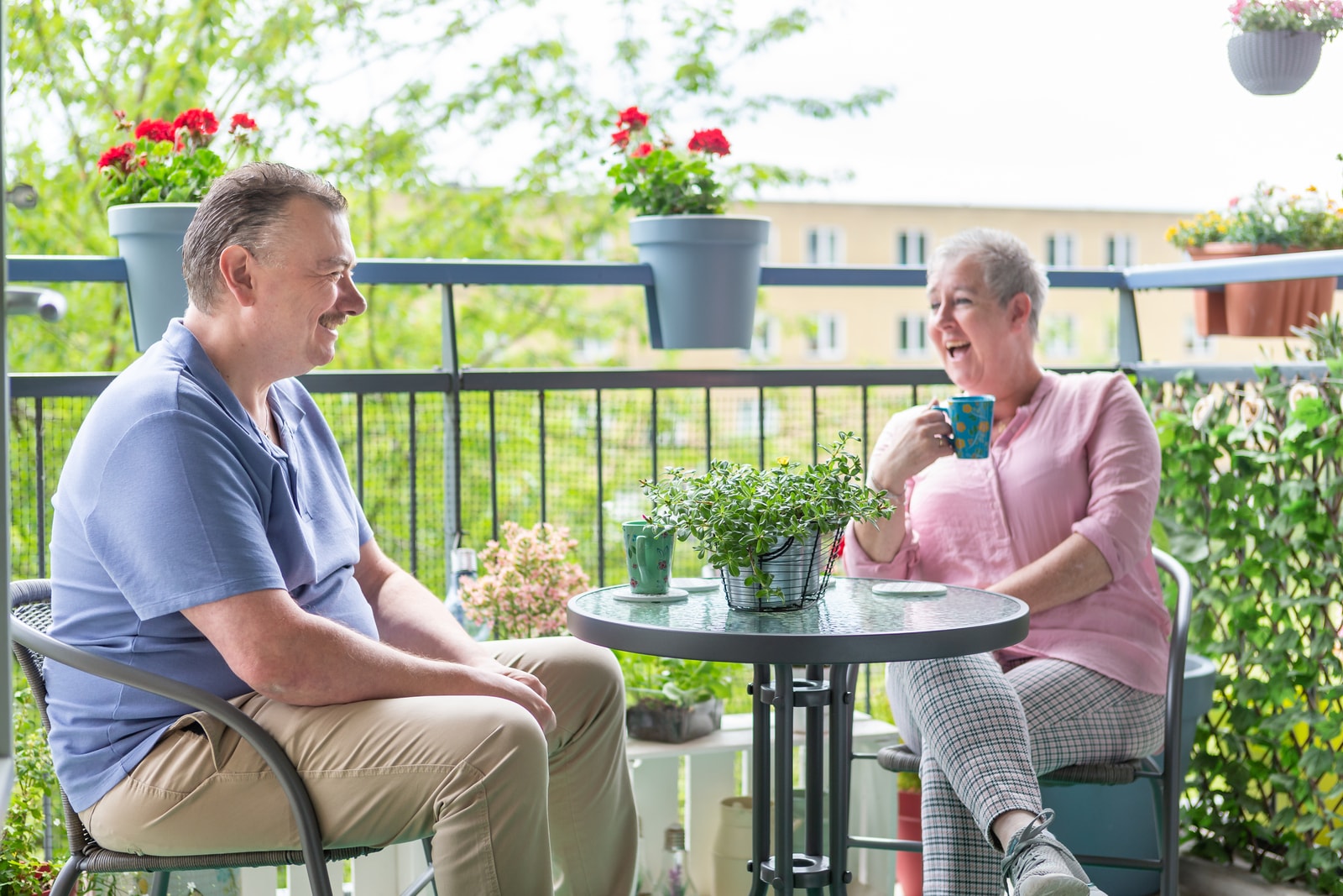 Herman en Patricia lachend aan de tafel op hun balkon