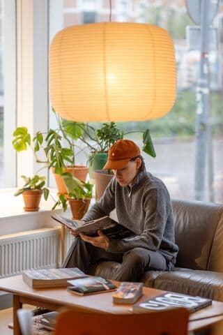 Woody van Overdijk bladert in een fotoboek en zit in de woonkamerhoek