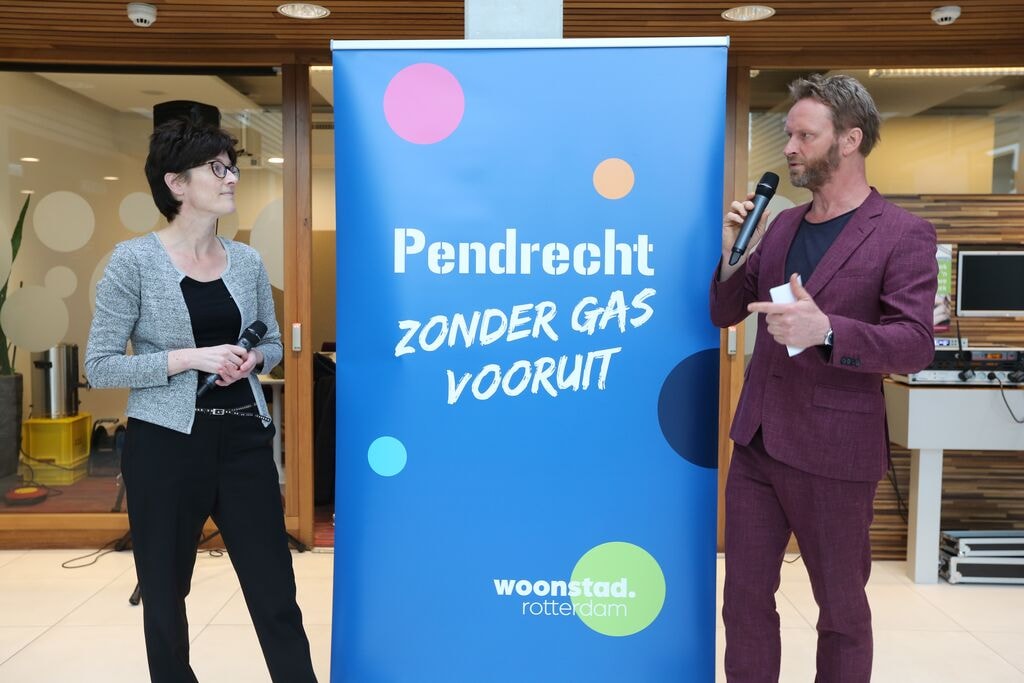 Twee medewerkers staan voor spandoek met de tekst 'Pendrecht zonder gas vooruit'